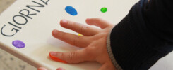 dettaglio mano con dito diponto di colore che lascia un'impronta su un supporto bianco