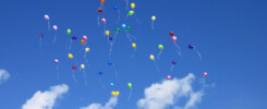 Palloncini colorati volano in cielo fra le nuvole