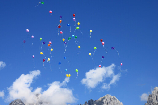 Palloncini colorati volano in cielo fra le nuvole
